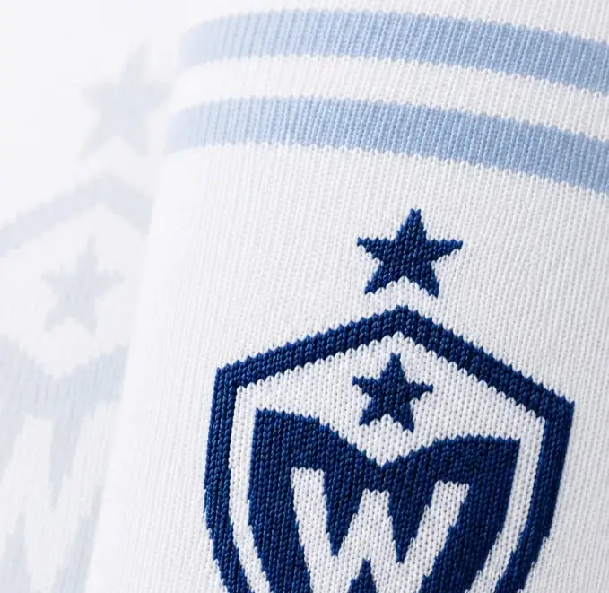 Detalle de escudo tejido en alta precisión sobre media blanca